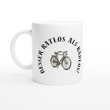 Eine schlichte, weiße Keramiktasse mit einem schwarzen Aufdruck. In der Mitte ist eine detaillierte Vintage-Illustration eines klassischen Fahrrads zu sehen. Halbkreisförmig um das Fahrrad herum steht in einer markanten Serifenschrift der humorvolle Spruch „BESSER RATLOS ALS RADLOS!“.