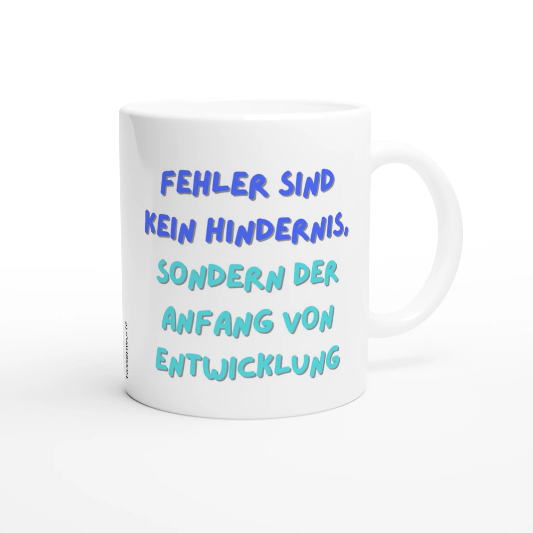 Weiße Keramiktasse mit dem blauen Schriftzug „Fehler sind kein Hindernis, sondern der Anfang von Entwicklung“ auf weißem Hintergrund.