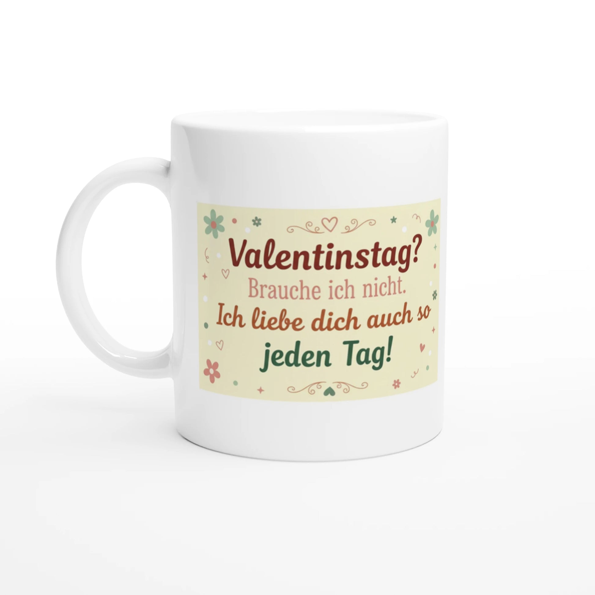 Weiße Keramiktasse auf einem Holztisch mit dem deutschen Spruch „Valentinstag? Brauche ich nicht. Ich liebe dich auch so jeden Tag!“, verziert mit kleinen Blumen und Herzen in Pastelltönen.