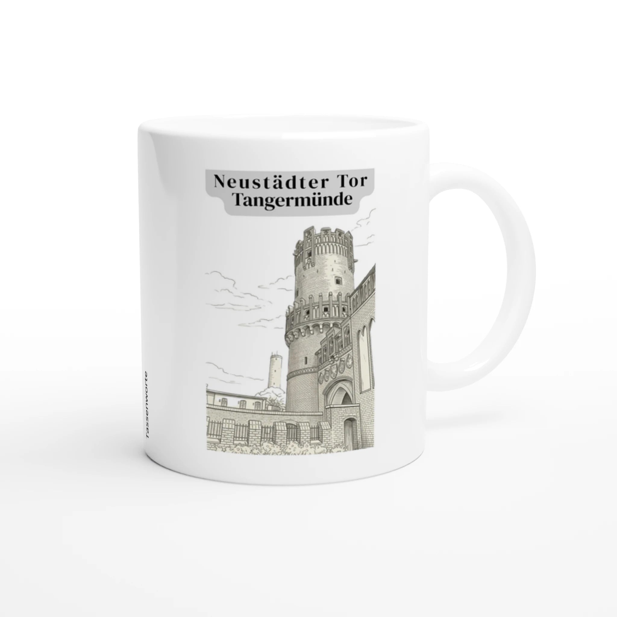 Eine weiße Keramiktasse mit einer detaillierten Grafik des Neustädter Tors in Tangermünde. Die Illustration zeigt den markanten Backsteinturm mit Zinnenkranz und Wappenfries in feinen grauen Linien. Über der Grafik steht in einer klassischen Serifenschrift der Schriftzug ‚Neustädter Tor Tangermünde‘ auf einem dezenten grauen Banner
