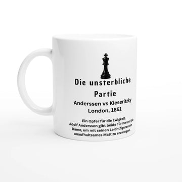 Detailaufnahme einer weißen Tasse mit dem Aufdruck „Die unsterbliche Partie“. Das Design enthält eine schwarze Schachkönig-Grafik, elegante florale Eck-Ornamente und eine Beschreibung des historischen Spiels von Anderssen gegen Kieseritzky.