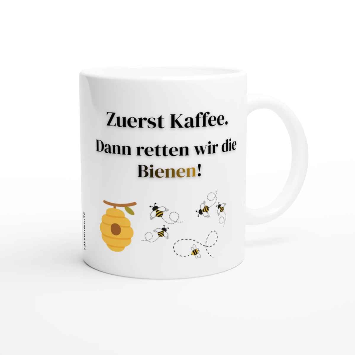 Weiße Keramiktasse mit schwarzem Spruch „Zuerst Kaffee. Dann retten wir die Bienen!“ und Grafik von Bienenstock und fliegenden Bienen von Tassenworte.