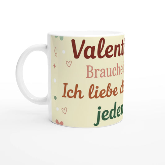 Weiße Keramiktasse mit einem vollflächigen, hellgelben Design-Element. In der Mitte steht der Spruch „Valentinstag? Brauche ich nicht. Ich liebe dich jeden Tag!“ in verschiedenen Braun- und Grüntönen. Das Design ist mit kleinen Herzen, Sternen und Schnörkeln verziert.