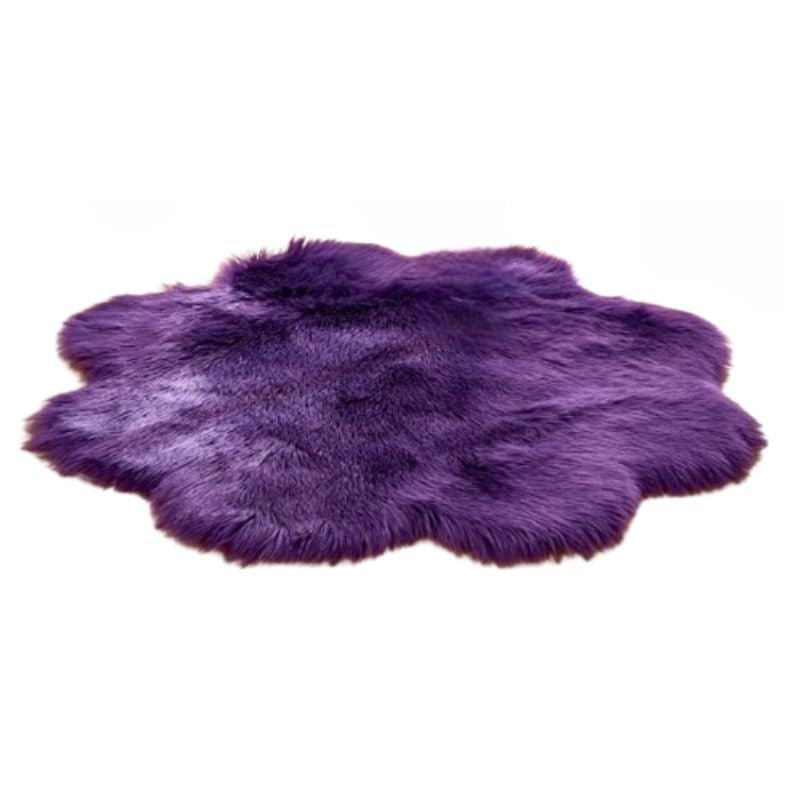 Lila Kunstfellteppich mit flauschiger, unregelmäßig runder Form auf weißem Hintergrund.