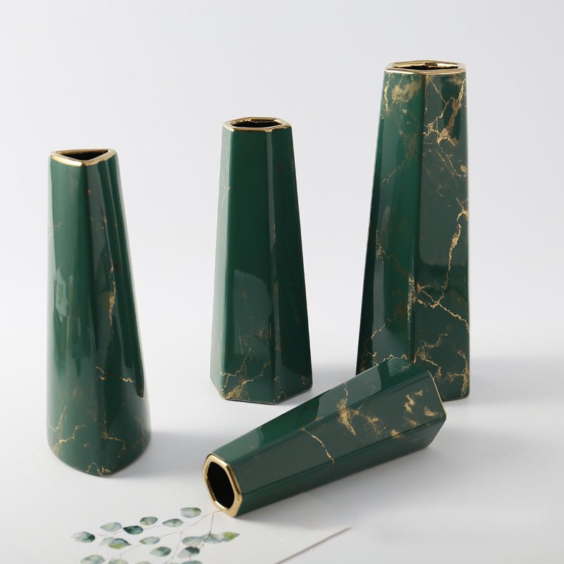 „Vier grüne Keramikvasen im Marmor-Look mit goldfarbenem Rand in verschiedenen Höhen; drei stehen, eine liegt vorne auf hellem Hintergrund.“