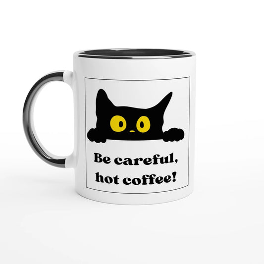 Weiße Keramiktasse mit schwarzem Akzent an Henkel und Rand. Das Motiv zeigt innerhalb eines schwarzen Rahmens eine hervorguckende schwarze Katze mit großen, gelben Augen. Darunter steht in fetter, schwarzer Serif-Schrift die Warnung „Be careful, hot coffee!“.
